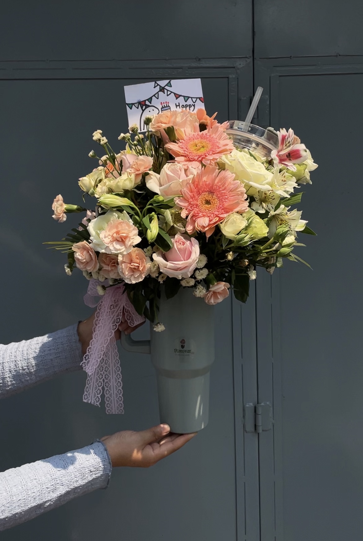 A charming arrangement of mixed fresh flowers beautifully styled in a reusable tumbler. This bouquet combines colorful blooms with a practical keepsake, making it a thoughtful and unique gift for any occasion.