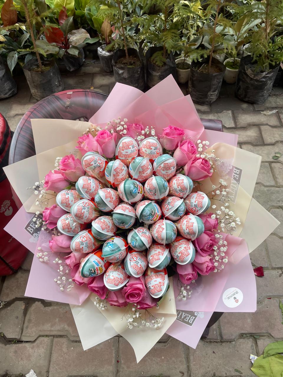 A generous combined gift arrangement featuring 20 fresh pink roses and 30 individual Kinder Joy chocolate treats.