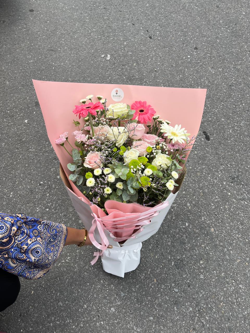 An artisan-crafted bouquet featuring premium pink roses and white carnations wrapped in elegant pastel paper.