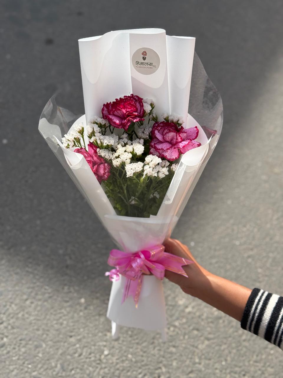 As flowers are natural products, the size, bloom stage, and shades of flowers may vary slightly depending on seasonal availability. White statice fillers may be replaced with gypsy flowers based on availability while maintaining the bouquet's overall design and elegance. The wrapping style may also vary slightly while ensuring a premium presentation. To keep the flowers fresh for longer, place the flowers in clean water and keep the bouquet away from direct sunlight and excessive heat.