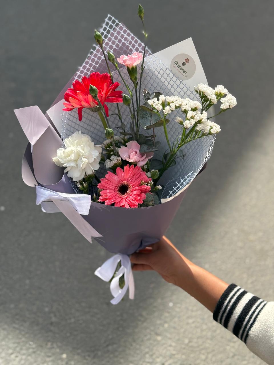 As flowers are natural products, the size, bloom stage, and shades of flowers may vary slightly depending on seasonal availability. White statice may be replaced with gypsy flowers based on availability while maintaining the bouquet's overall design and premium appearance. The wrapping style may also vary slightly while ensuring an elegant presentation. To keep the flowers fresh for longer, place them in clean water and keep the bouquet away from direct sunlight and excessive heat.