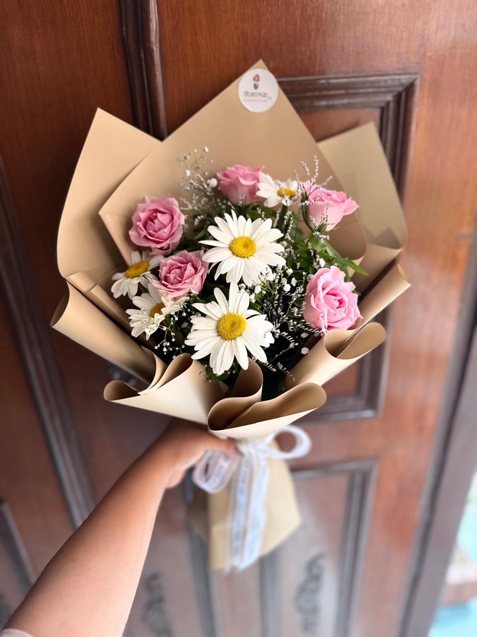 As flowers are natural products, the size, bloom stage, and shades of flowers may vary slightly depending on seasonal availability. White daisies may be replaced with white gerbera flowers based on availability while maintaining the bouquet's overall design and elegance. The wrapping style may also vary slightly while ensuring a premium presentation. To keep the flowers fresh for longer, place them in clean water and keep the bouquet away from direct sunlight and excessive heat.