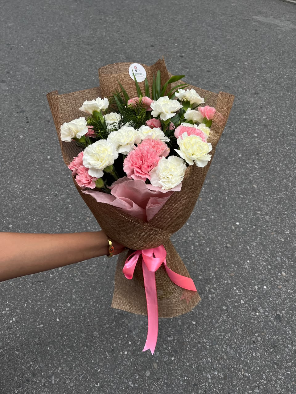 As flowers are natural products, the size, bloom stage, and shades of white and pink carnations may vary slightly depending on seasonal availability. The wrapping style may also vary while maintaining the bouquet's premium presentation and elegant appearance. To keep your flowers fresh for longer, place them in clean water, trim the stems at an angle, and keep the bouquet away from direct sunlight and excessive heat.