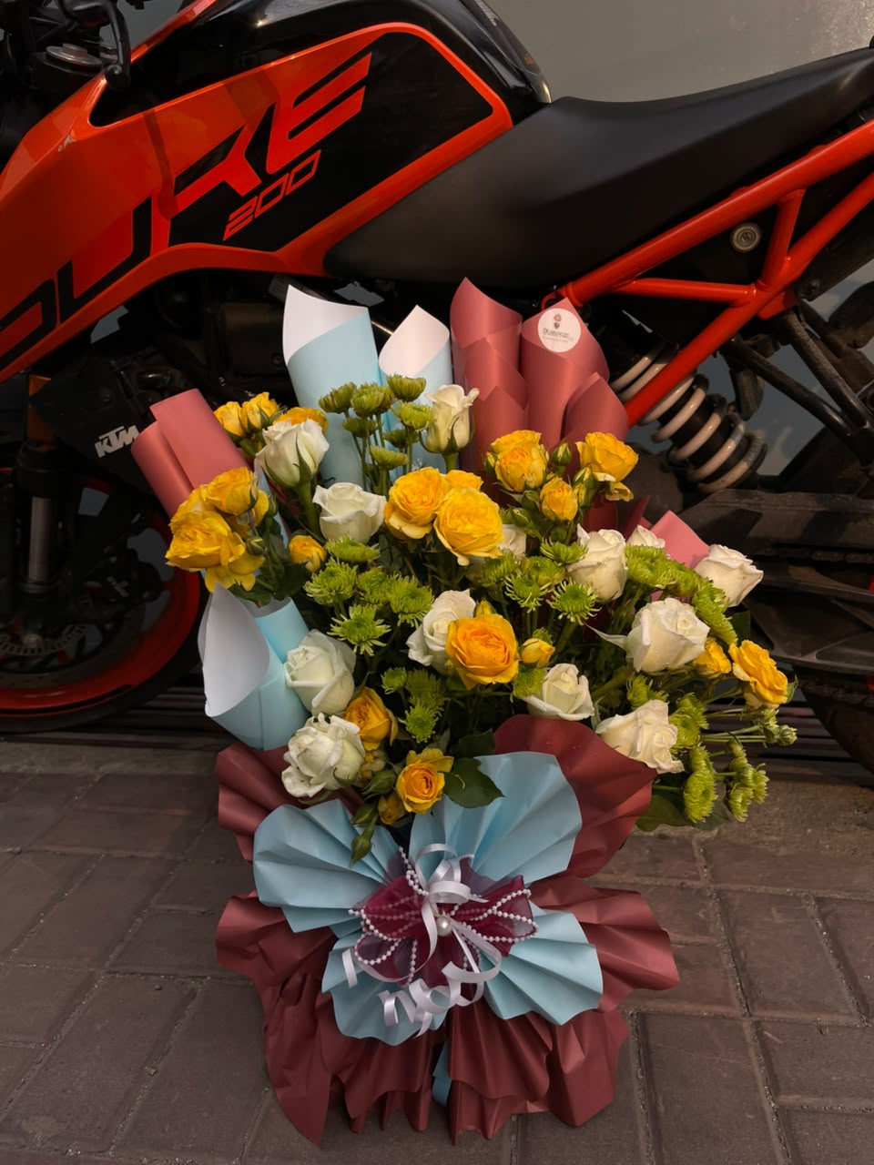 As flowers are natural products, the size, bloom stage, and shades of flowers may vary slightly depending on seasonal availability. Green daisies may be replaced with other suitable seasonal flowers based on availability while preserving the bouquet's overall design, color harmony, and premium appearance. The heavy wrapping style may also vary slightly while ensuring an elegant and luxurious presentation. To keep the flowers fresh for longer, place them in clean water and keep the bouquet away from direct sunlight and excessive heat.