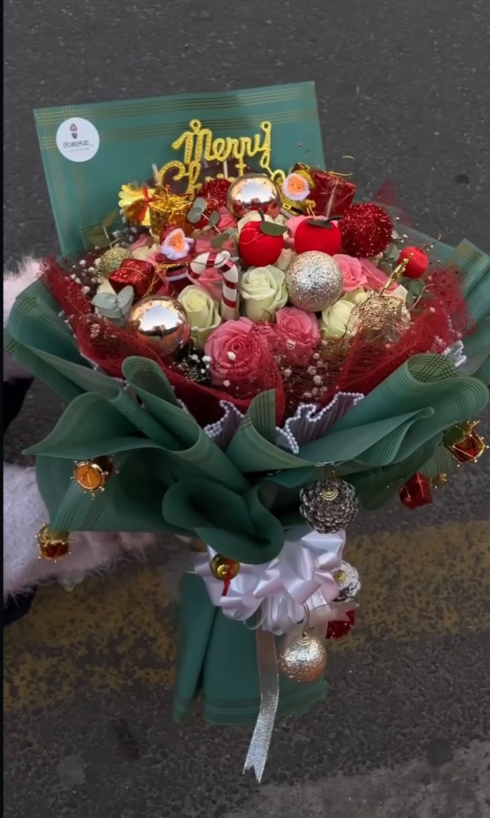 Christmas props and decorative accessories may vary based on availability. Flower colors and bloom stages may vary naturally. In case any flower, decoration, or wrapping material is unavailable, a suitable replacement of similar value and style may be used while maintaining the festive look and premium presentation of the bouquet.